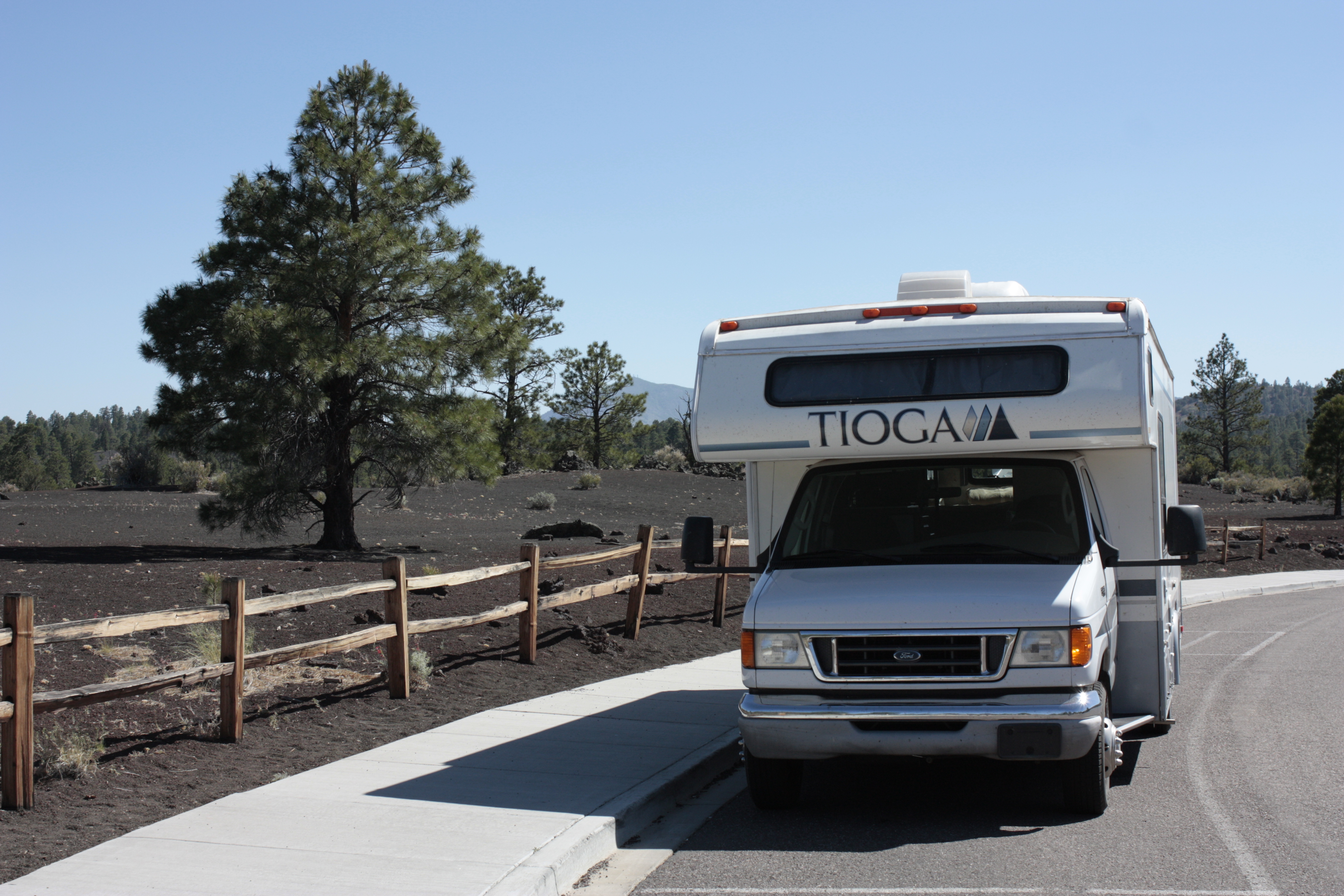 The front of the Tioga parked beside a pine tree and open landscape.